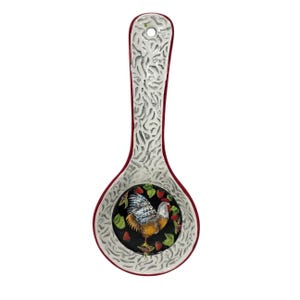 May include: A ceramic spoon rest featuring a central circular basin decorated with a painted rooster, green leaves, and red berries on a black background. The handle and border have a textured, light gray finish with a deep red outer rim.
