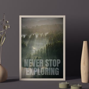 Può includere: Una stampa incorniciata con una scena di foresta nebbiosa e il testo "NEVER STOP EXPLORING" in lettere bianche.