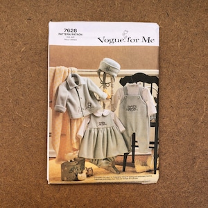 May include: Vogue for Me pattern 7628 for a baby outfit. The pattern includes a blue fleece jacket, a blue overall, a blue dress with a white collar, and a blue hat. The pattern is for one size, taille unique.