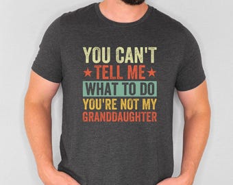 May include: A dark gray t-shirt with a vintage-style graphic that reads "You can't tell me what to do you're not my granddaughter".