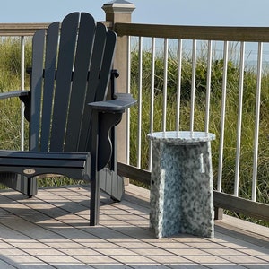 May include: A black adirondack chair and a white marble side table on a wooden deck with a view of the ocean.