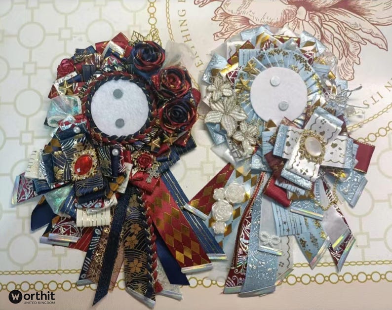 May include: Two decorative rosettes with intricate ribbon designs. One features red, navy, and gold ribbons with a central white circle and a red jewel. The other has light blue, white, and gold ribbons with a central white circle and a decorative brooch.