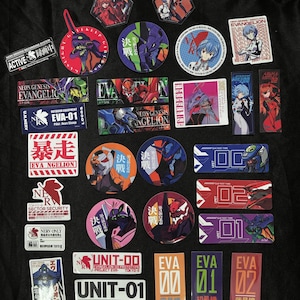 May include: A collection of colorful anime-themed stickers and badges featuring characters and logos from the Neon Genesis Evangelion series. The items include various shapes, sizes, and designs, with Japanese text.