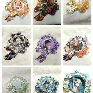 May include: A collection of handmade decorative brooches. Each brooch features a central image, surrounded by ribbons, fabric flowers, and embellishments in various colors, including gold, red, purple, and blue. The brooches have a circular or oval shape.