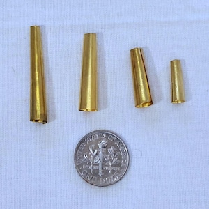 May include: Four gold-colored metal cones of varying sizes, with the smallest cone being about the size of a dime.