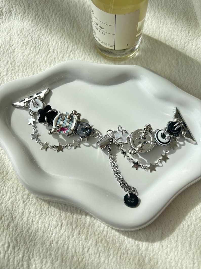 Upcycled black & white button iWatch band with star charms on white ceramic dish