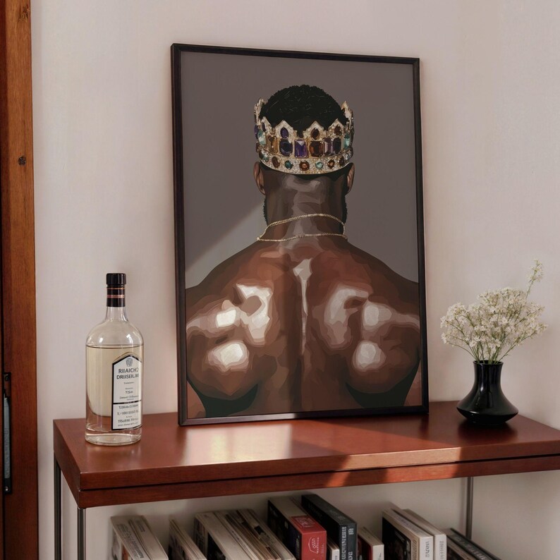 Pode incluir: Impress&atilde;o de arte emoldurada com uma figura musculosa usando uma coroa de joias e uma corrente de ouro. A obra de arte &eacute; exibida em uma prateleira de madeira escura, junto com uma garrafa de licor e um pequeno vaso de flores brancas. Fundo cinza escuro.