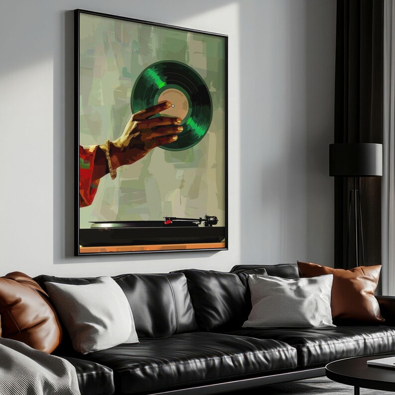 May include: A framed art print featuring a hand holding a green vinyl record. The artwork has a retro aesthetic, with a turntable visible at the bottom. The hand is wearing a bracelet and a red and green patterned sleeve.