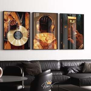 以下が含まれることがあります： 3つの額入りアートプリントのセット。1つは金色のレコード盤を持つ人物、もう1つはヘッドホンをつけた人物、3つ目は「PLAY」と書かれたボタンを押す手元が描かれています。