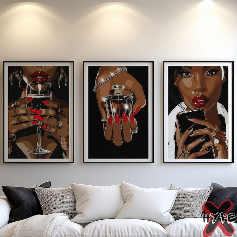 May include: Three framed art prints featuring a woman with red lipstick and nails. The prints are set against a white wall above a white couch. The woman in the left print is holding a glass of wine, the woman in the center print is holding a bottle of perfume, and the woman in the right print is holding a smartphone.