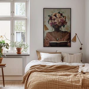 Puede incluir: Un dormitorio con una cama hecha con una manta marr&oacute;n y almohadas a rayas blancas y marrones. Un cuadro enmarcado de una mujer con flores en la cabeza cuelga de la pared sobre la cama.