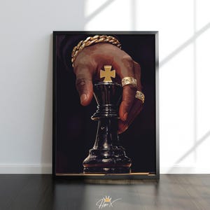 May include: Framed art print featuring a hand holding a black chess king piece with a gold cross on top. The hand is adorned with gold rings and a gold bracelet. The background is dark.