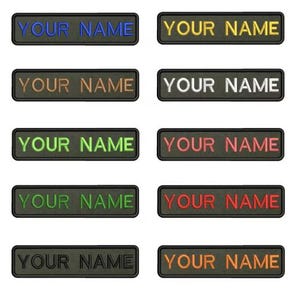Puede incluir: Un conjunto de parches rectangulares con el texto "YOUR NAME" bordado en varios colores, incluyendo azul, amarillo, marrón, blanco, verde, rojo y naranja. Cada parche tiene un borde negro.