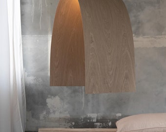 May include: A wooden arch-shaped pendant light fixture hangs from the ceiling in a room with a concrete wall and a wooden bench. The light fixture is made of light brown wood and has a warm, inviting glow.