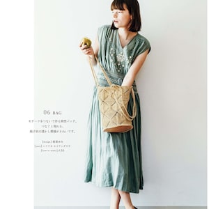 Può includere: Una borsa marrone chiaro, a trama aperta, con un motivo geometrico, portata da una persona che indossa un vestito verde salvia. La borsa ha una base in pelle marrone chiaro e un cinturino abbinato. Il vestito ha ricami floreali.