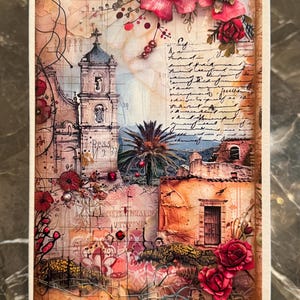 May include: A mixed media artwork featuring a church with a bell tower, palm trees, and buildings. The artwork incorporates script, red flowers, and a textured background. The piece is framed in a white border.