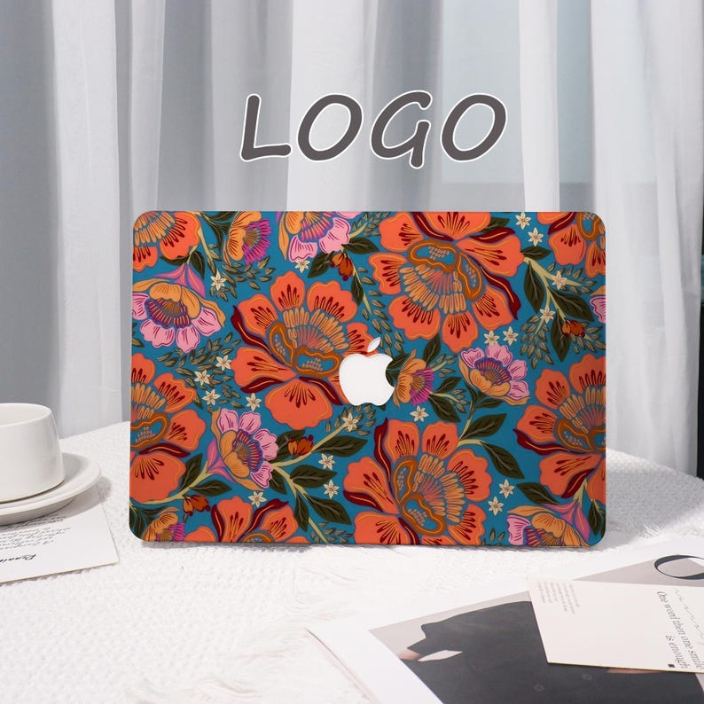 K&ouml;nnte beinhalten: Eine Laptop-H&uuml;lle mit einem lebendigen Blumenmuster in Orange, Rosa und Wei&szlig; auf t&uuml;rkisfarbenem Hintergrund. Die H&uuml;lle zeigt das Apple-Logo und das Wort "LOGO" in einer Schreibschrift. Die H&uuml;lle befindet sich auf einer wei&szlig;en Oberfl&auml;che.