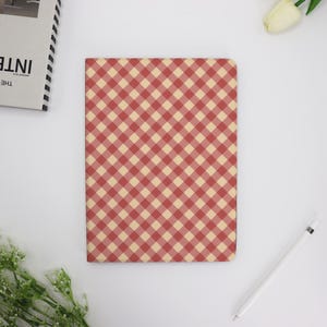 May include: A red and cream gingham patterned notebook cover.
