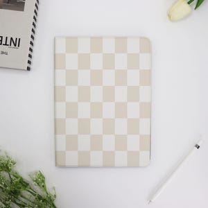 Op de afbeelding: Een iPad-hoes met een geruit patroon in wit en beige. De hoes is gemaakt van een zacht, duurzaam materiaal en heeft een strak, modern ontwerp.