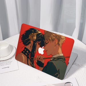 Peut inclure: Coque d'ordinateur portable rouge avec une illustration de style anime de deux personnages dans une pose romantique. L'étui a un logo Apple blanc et un accessoire doré. Le fond est rouge.