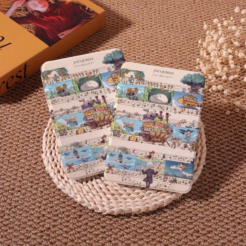 May include: Two rectangular notebooks with a whimsical illustration featuring musical notes, cartoon characters, and the text "JOE'S JUBILEE" in English and Japanese. The notebooks have a cream-colored background and are placed on a woven mat.