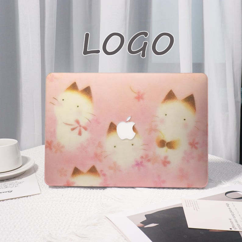 K&ouml;nnte beinhalten: Eine rosa Laptop-H&uuml;lle mit einem sich wiederholenden Muster von Cartoon-Katzen mit braunen Ohren und Akzenten sowie rosa floralen Details. Die H&uuml;lle hat das Apple-Logo und das Wort "LOGO" oben in der Mitte.