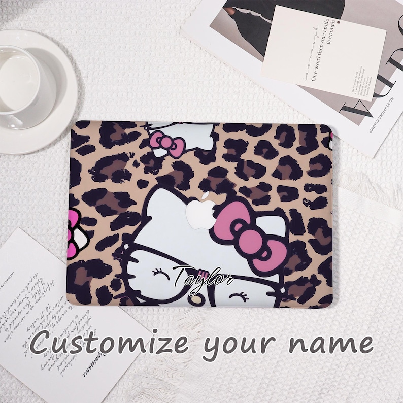Pu&ograve; includere: Una custodia per laptop con un design di Hello Kitty bianco con un fiocco rosa e uno sfondo con stampa leopardata. Contiene il testo "Taylor" e "Customize your name".