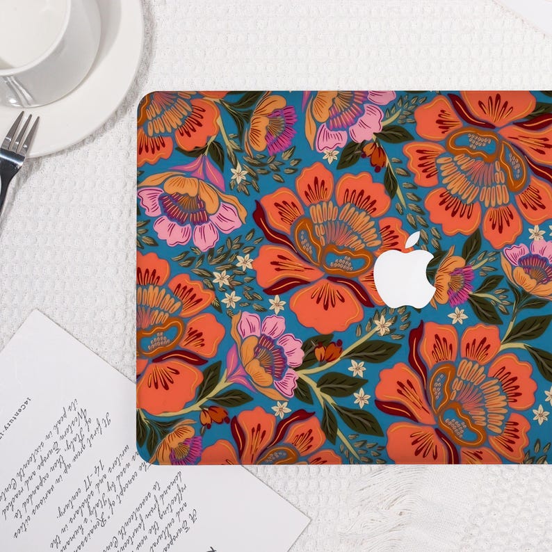 K&ouml;nnte beinhalten: Eine Laptop-H&uuml;lle mit einem lebendigen Blumenmuster in Orange, Rosa und Wei&szlig; auf einem t&uuml;rkisblauen Hintergrund. Das Design umfasst gro&szlig;e stilisierte Blumen und Bl&auml;tter, mit dem Apple-Logo sichtbar. Die H&uuml;lle liegt auf einer wei&szlig;en Oberfl&auml;che.