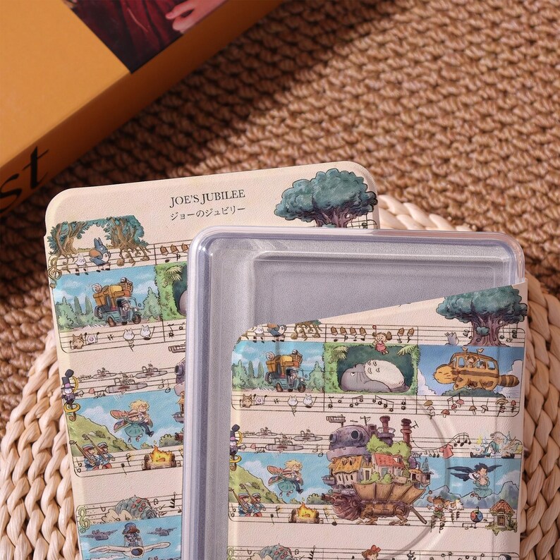 May include: A beige rectangular container with a clear lid. The container is decorated with a whimsical illustration featuring characters and scenes, with musical notes and the text "JOE'S JUBILEE" in English and Japanese.