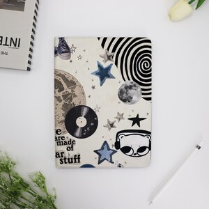 Op de afbeelding: Een witte achtergrond met een collage van afbeeldingen, waaronder een plaat, een beer met een koptelefoon, een maan en sterren. De tekst "We are made of star stuff" is linksonder gedrukt.