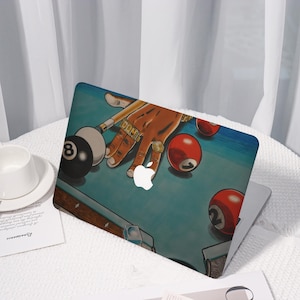 May include: Laptop case featuring a pool table design with a hand wearing gold rings, holding a pool cue. The design includes red and black pool balls, and the Apple logo.