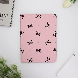 May include: A pink iPad case with a black bow pattern.