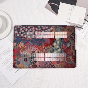 May include: A laptop case with a colorful abstract design in red, blue, and gold. The case has a series of white vertical vents and small black feet. The design includes the text "One word then one smile is enough".