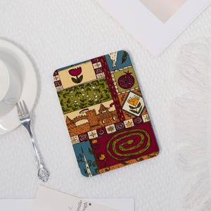 Könnte beinhalten: Rechteckiger Untersetzer mit einem farbenfrohen, gemusterten Design. Das Design zeigt ein Schloss, Blumen und eine Schlange im Patchwork-Stil. Der Untersetzer hat einen cremefarbenen Hintergrund und ist wahrscheinlich aus Stoff.