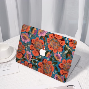 May include: A laptop with a floral design case. The case features large orange and pink flowers with green leaves on a teal background. The Apple logo is visible in the center of the laptop.