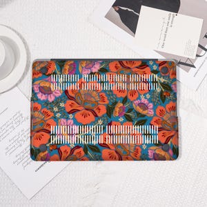 K&ouml;nnte beinhalten: Eine Laptop-H&uuml;lle mit einem lebendigen Blumenmuster. Die H&uuml;lle zeigt gro&szlig;e orangefarbene und rosa Bl&uuml;ten mit gr&uuml;nen Bl&auml;ttern und wei&szlig;en Akzenten auf einem t&uuml;rkisfarbenen Hintergrund. Die H&uuml;lle hat eine Reihe wei&szlig;er vertikaler Linien.