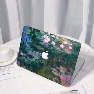 Peut inclure: Une coque d'ordinateur portable ornée d'une peinture impressionniste colorée de nénuphars. Le design comprend des nuances de vert, de bleu, de rose et de blanc. Le logo Apple est visible. L'ordinateur est posé sur une surface blanche.