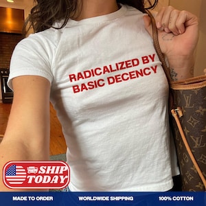 May include: White t-shirt with the red text "RADICALIZED BY BASIC DECENCY". The shirt is made of 100% cotton. The shirt is a crew neck style.