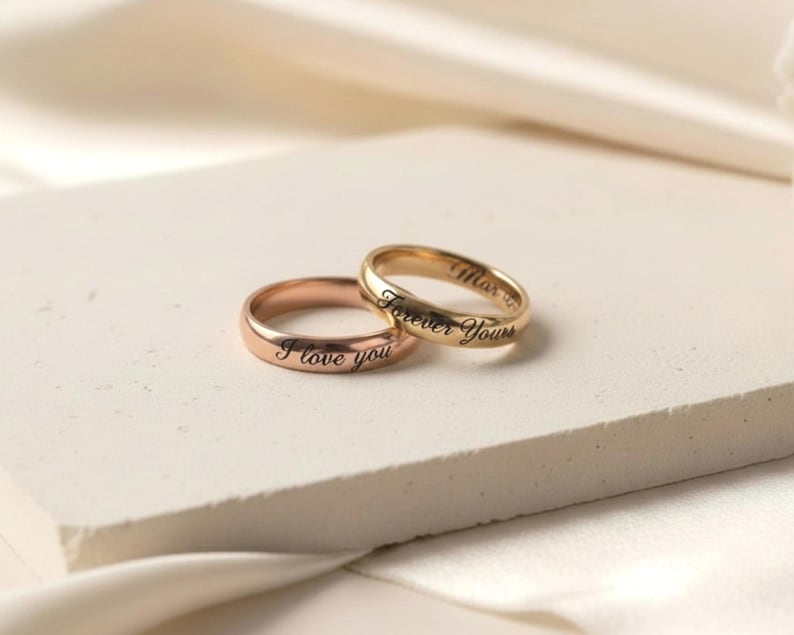 Peut inclure: Deux bagues en m&eacute;tal poli avec des anneaux arrondis. Une bague est de couleur or rose et grav&eacute;e avec le texte I love you. La deuxi&egrave;me bague est de couleur or jaune et grav&eacute;e avec le texte Forever Yours dans une police d'&eacute;criture cursive.
