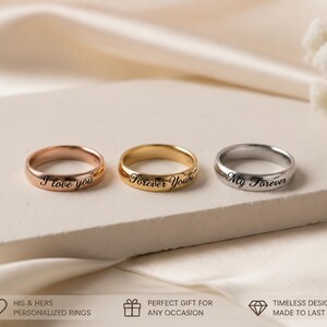 Peut inclure: Trois bagues en m&eacute;tal aux tons or rose, or jaune et argent. Chaque bague pr&eacute;sente un anneau lisse et arrondi avec un texte grav&eacute; en noir. La bague en or rose porte l'inscription I love you, celle en or jaune Forever Yours et l'argent&eacute;e My Forever.