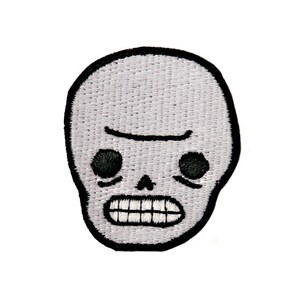 May include: A white embroidered skull patch with black outlines. The skull has a simple design with two black eyes, a black nose, and a black mouth with white teeth.
