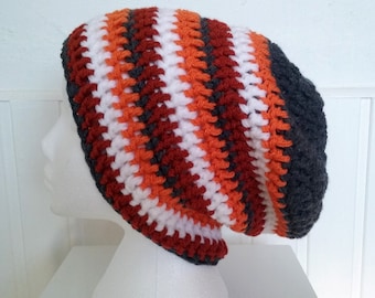 Op de afbeelding: Een gebreide beanie met strepen van witte, oranje en rode garen. De muts heeft een grijze rand.