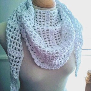 May include: White crochet shawl with a delicate openwork pattern. The shawl is draped around a mannequin's neck and shoulders.