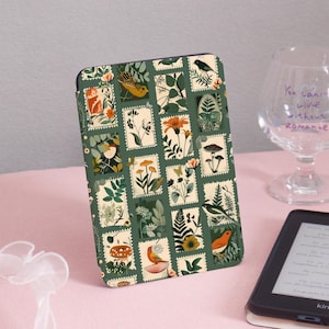 Puede incluir: Una funda verde para Kindle Paperwhite con un diseño vintage de flores y pájaros. La funda presenta un patrón repetitivo de cuadrados pequeños con imágenes de flores, pájaros y hongos.