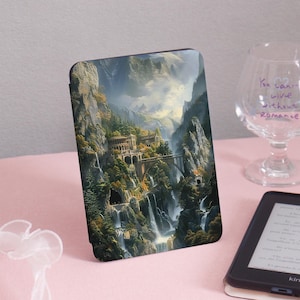 May include: A tablet case featuring a detailed landscape painting of a mountain valley with waterfalls, bridges, and buildings. The artwork is in shades of green, brown, and blue, with a bright sky. The case is on a pink surface.