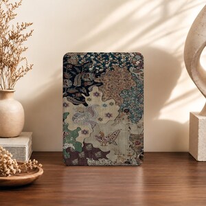 May include: A rectangular tablet case featuring a complex, multi-colored batik-style pattern with interlocking organic shapes. The design incorporates intricate floral motifs, stylized bird figures, and a palette of deep navy, tan, cream, and muted green.