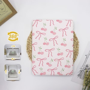 May include: A pink and white laptop sleeve with a repeating pattern of cherries and bows. The sleeve is made of a soft, durable material and is perfect for protecting your laptop from scratches and bumps.