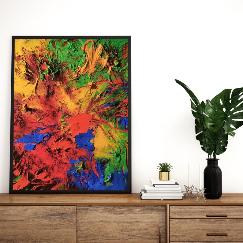 K&ouml;nnte beinhalten: Abstraktes Gem&auml;lde in einem schwarzen Rahmen mit leuchtenden Farben in Rot, Gelb, Gr&uuml;n und Blau. Das Gem&auml;lde wird auf einem Holzregal mit einer Vase und einer Topfpflanze ausgestellt.