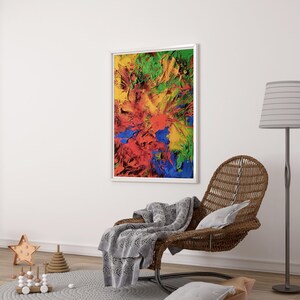 K&ouml;nnte beinhalten: Abstraktes Gem&auml;lde in einem wei&szlig;en Rahmen mit einem bunten Wirbel aus roter, gelber, gr&uuml;ner und blauer Farbe. Das Gem&auml;lde h&auml;ngt an einer wei&szlig;en Wand &uuml;ber einem Korbstuhl mit einer grauen Wolldecke.