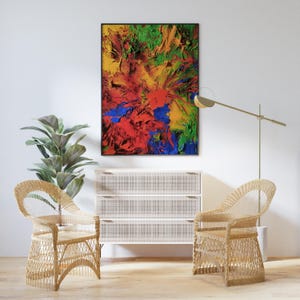 K&ouml;nnte beinhalten: Zwei Korbst&uuml;hle mit einer wei&szlig;en Kommode und einem gerahmten abstrakten Gem&auml;lde mit roter, gelber, gr&uuml;ner und blauer Farbe. Das Gem&auml;lde h&auml;ngt an einer wei&szlig;en Wand.